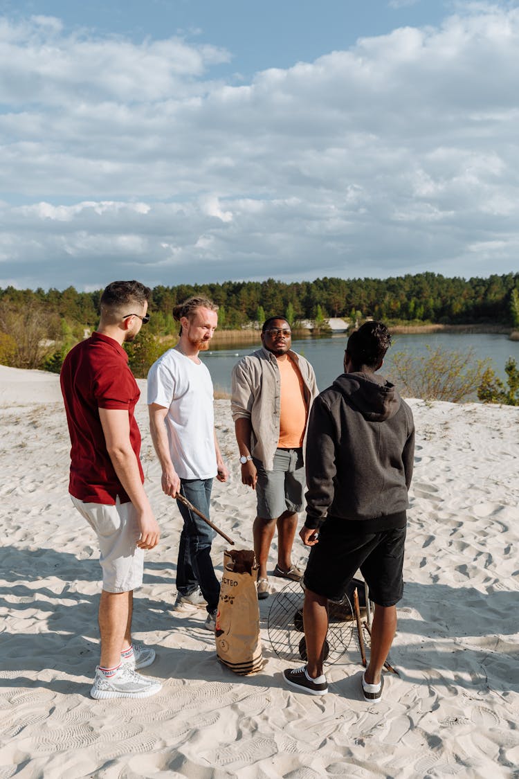 Group Of Men Standing Around A Barbecue Grill And Talking