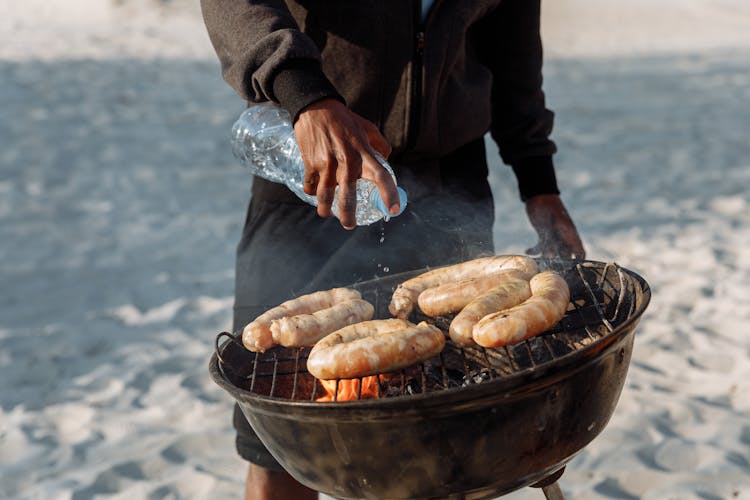 A Person Sprinkling Water On The Griller 