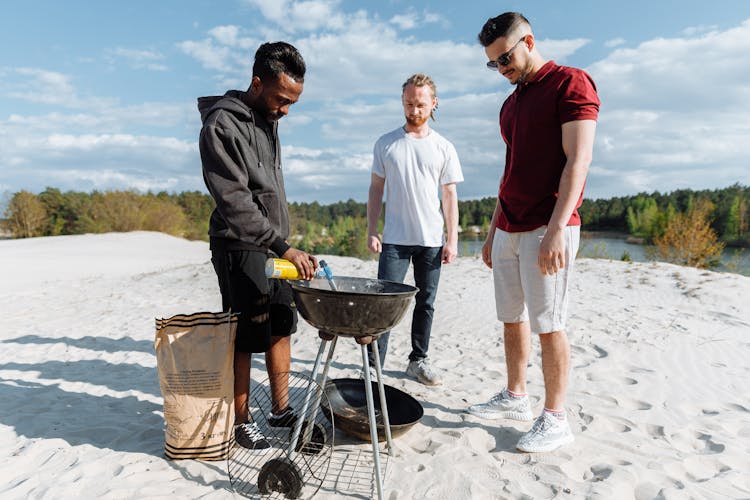 A Man Lighting Up A Barbecue Griller With A Torch