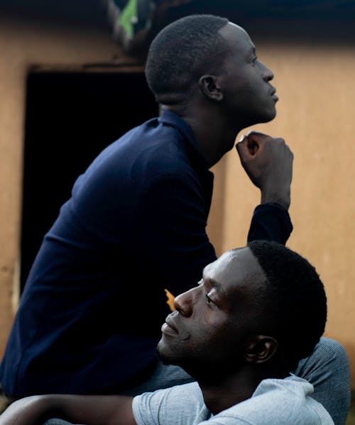 Men Sitting Beside Each Other in Opposite Directions