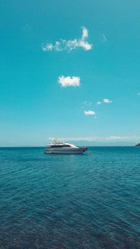 A sleek yacht floats quietly in the ocean under a clear blue sky, offering tranquility and elegance.
