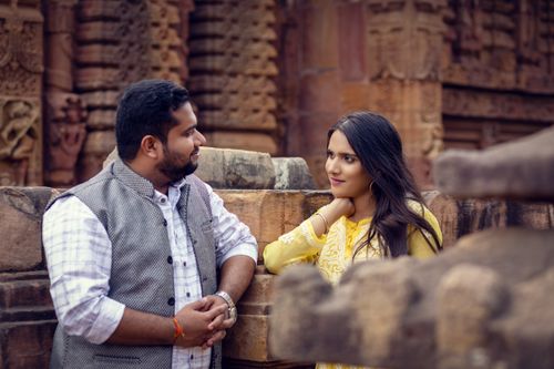 Free A couple smiling and chatting at an ancient stone temple with rich carvings. Stock Photo