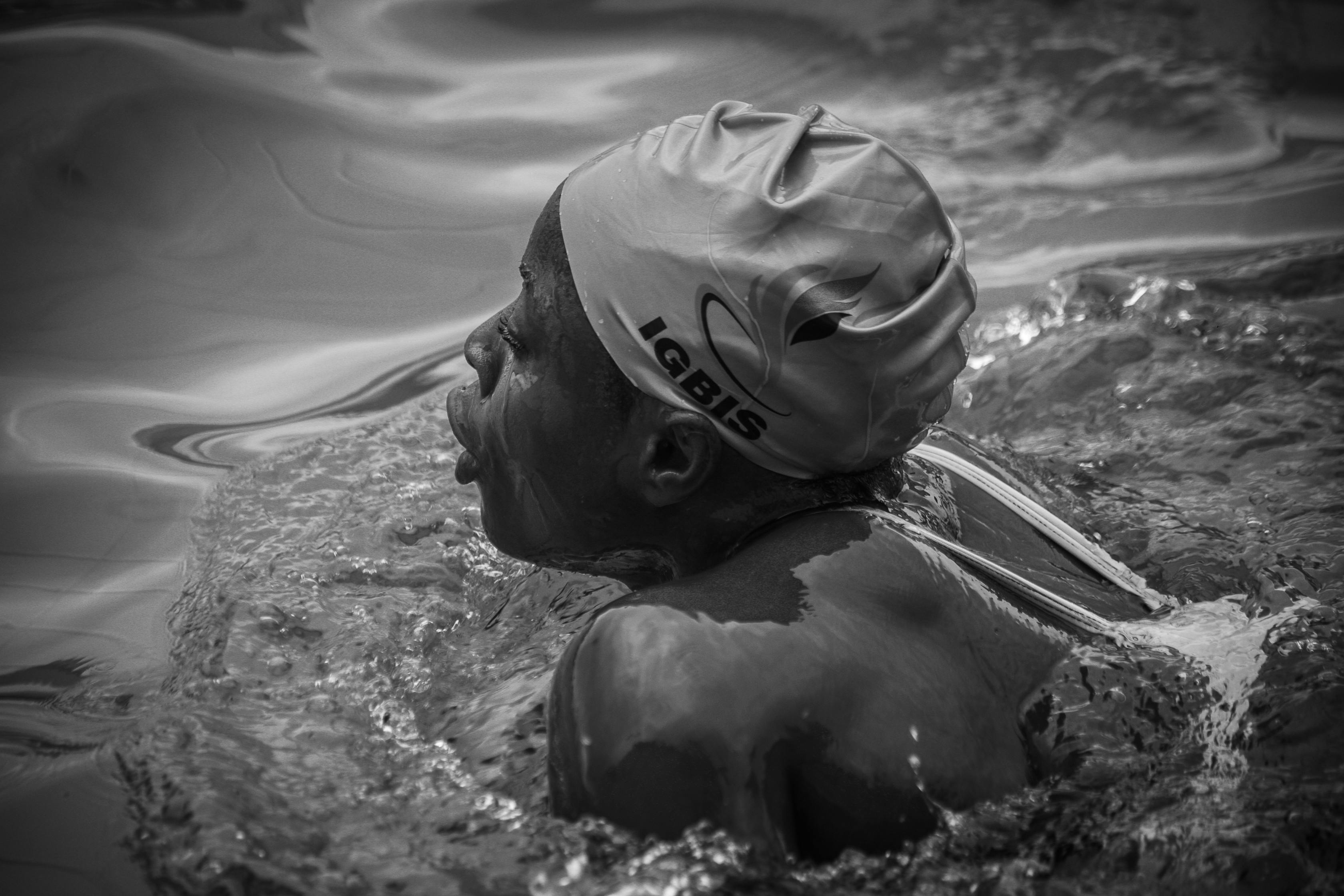 A black and white photograph of a swimmer in Nigeria, emphasizing movement and sport.