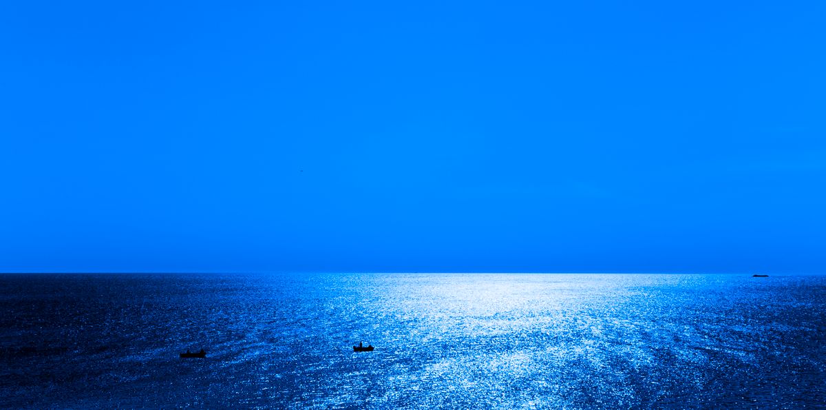 Open sea dotted with boats under a wide sky