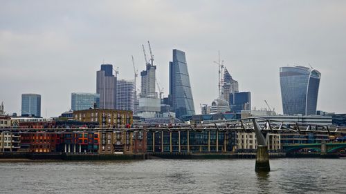 Free View of modern skyscrapers and Millennium Bridge in London's urban skyline. Stock Photo