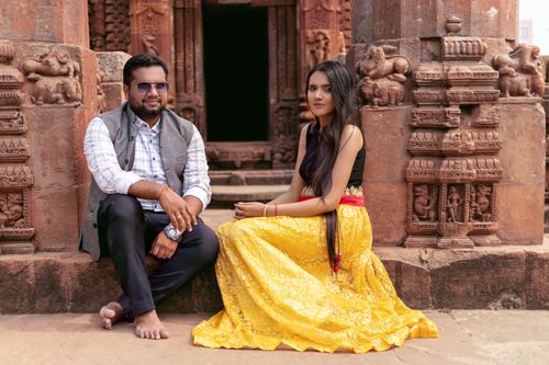 Free A couple sitting in traditional attire at the entrance of an ancient Indian temple, showcasing cultural heritage. Stock Photo