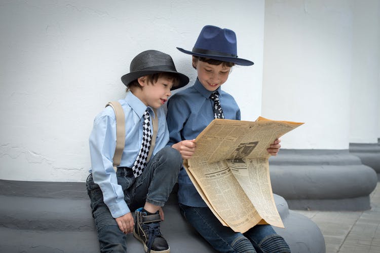 Boys Wearing Hats Reading Newspaper