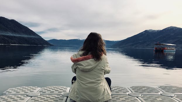 A woman sits on a dock, gazing at the tranquil Lake Villarrica in Pucón, Chile.