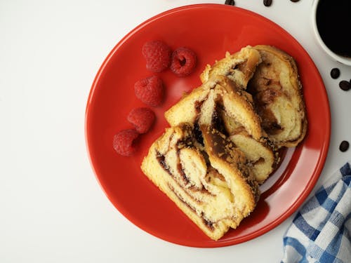 Slices of Cake and Raspberries on a Red Plate