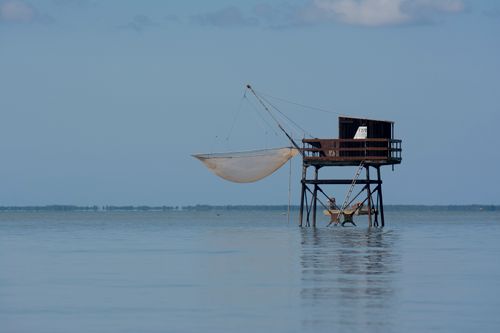 Free A tranquil fishing hut stands above calm lake waters, equipped with a net. Stock Photo
