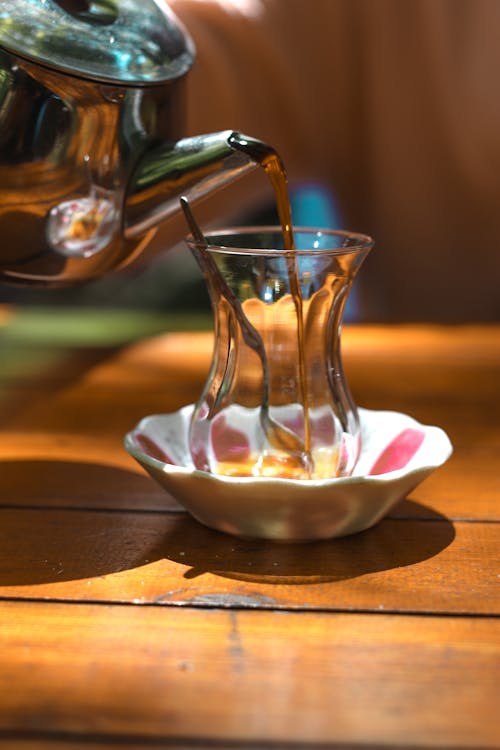 Pitcher Pouring Liquid Into a Clear Glass on a Bowl