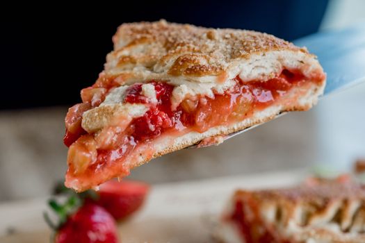 Delicious close-up of a freshly baked strawberry rhubarb pie slice on a spatula.