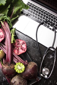 扁平布局的新鲜蔬菜、水果、听诊器和笔记本电脑，有助于促进健康生活方式