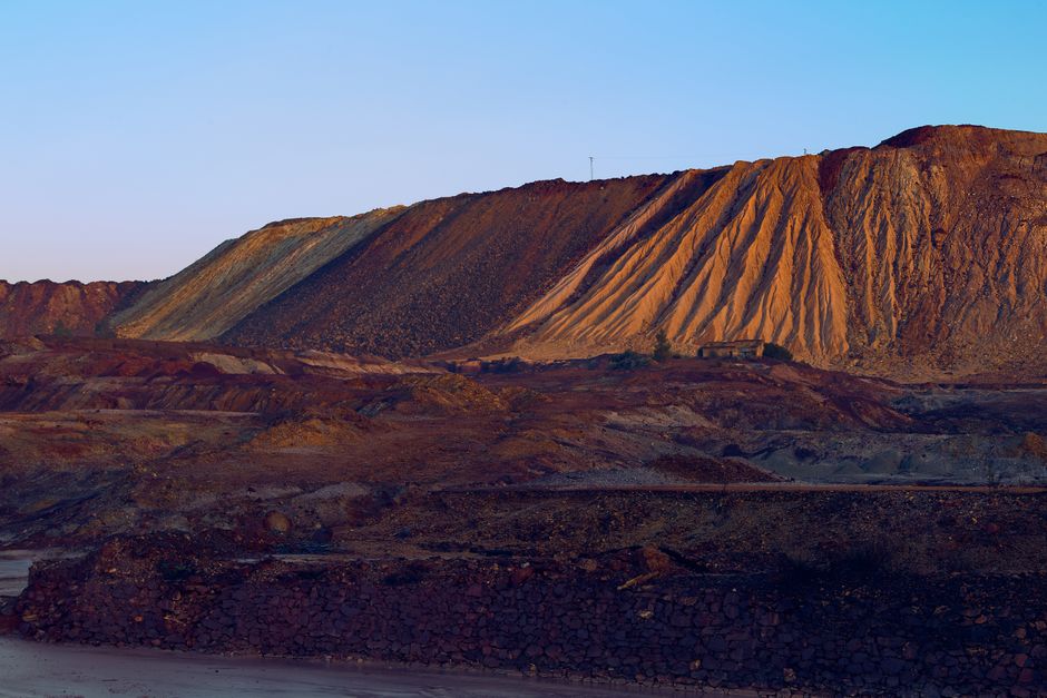 A striking view of a mining site showcasing rugged hills and mineral textures at sunset.