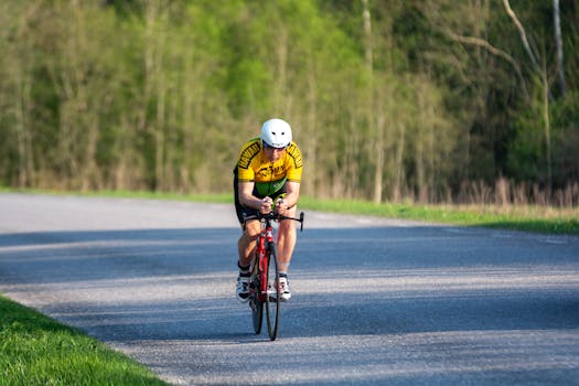 A solo cyclist racing on a scenic rural road in vibrant athletic gear.