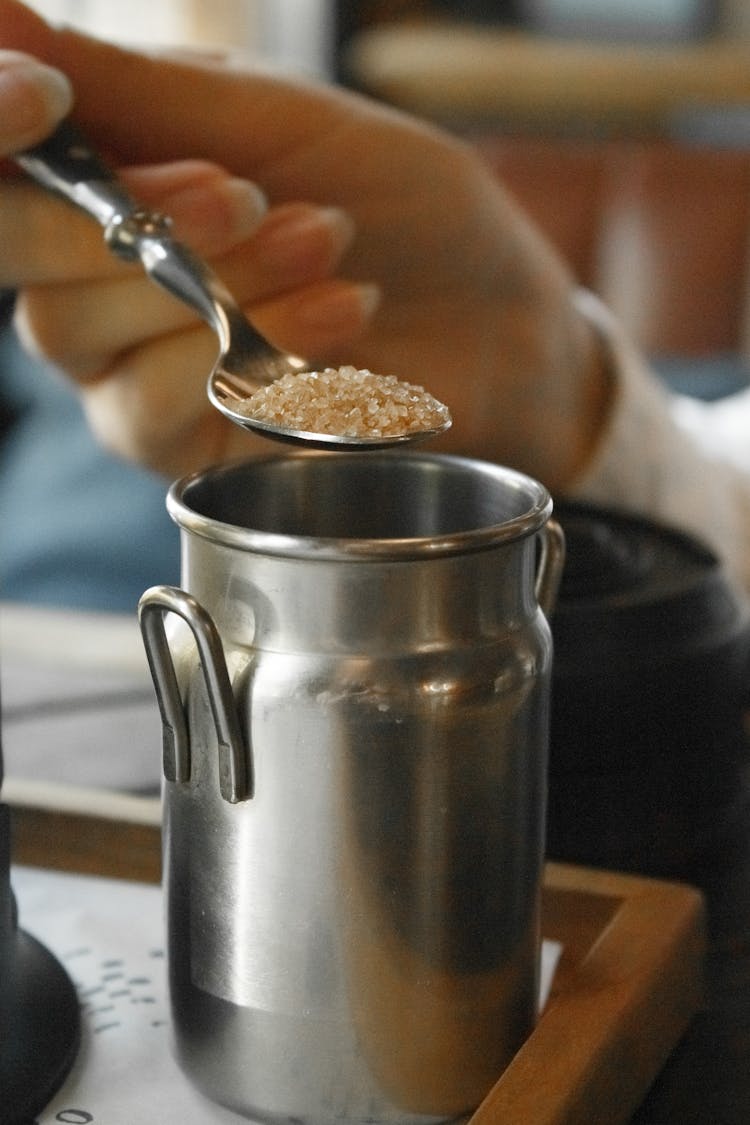 A Person Scooping A Teaspoon Of Sugar