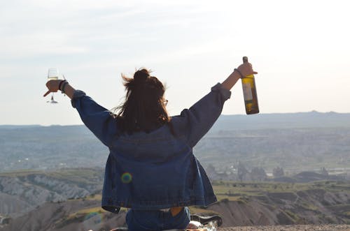 A Person Sitting on the Mountain Top Holding Champagne