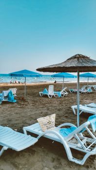 Tranquil beach setting with white chairs, blue umbrellas, and a serene sea view.