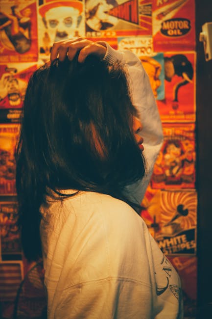 Profile view of a young woman in front of vintage posters, indoors.