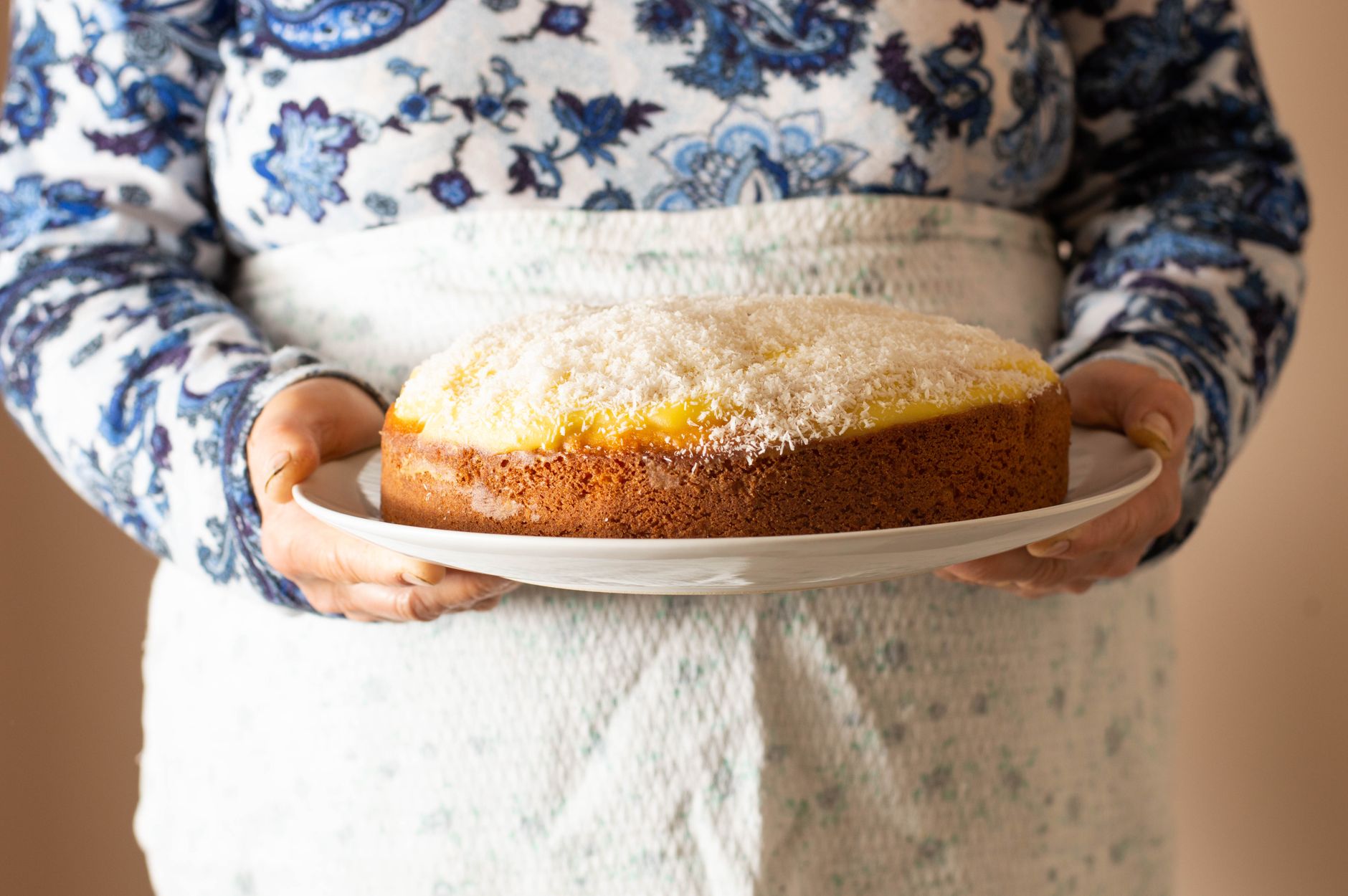 Slice of moist coconut cake with light frosting and coconut flakes
