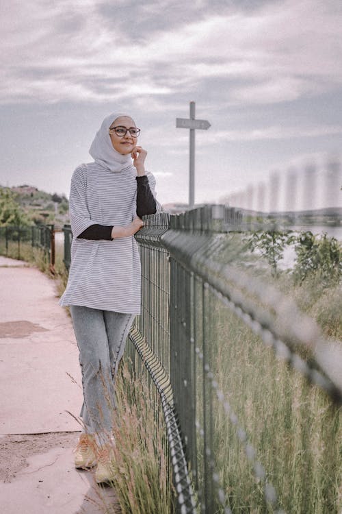 Woman Wearing Hijab Leaning on Fence