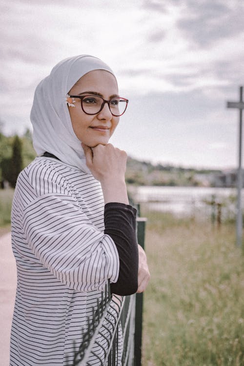 Free A Woman in a Hijab Leaning on a Fence Stock Photo