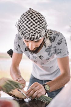 A man skillfully slices pineapple outdoors. Middle Eastern attire, summer vibe.