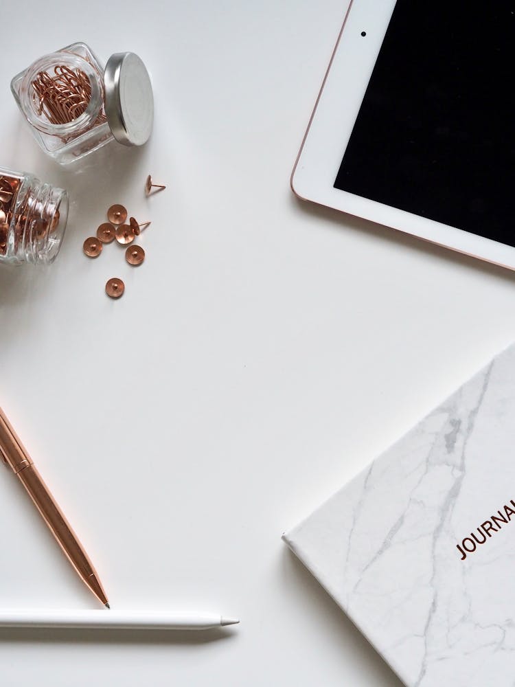 White Ipad On The Table Near Small Clear Glass Jars