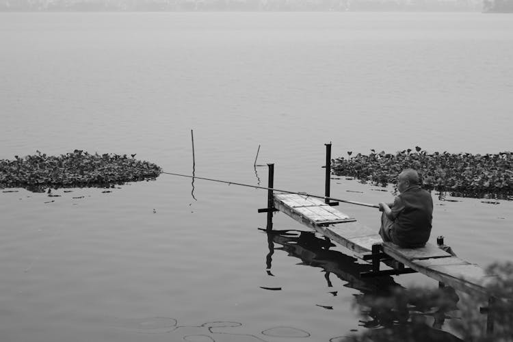 Monochrome Shot Of An Elderly Man Fishing