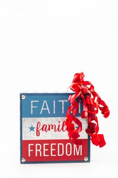 Patriotic sign featuring faith, family, freedom text with red, white, and blue design and ribbon accent.