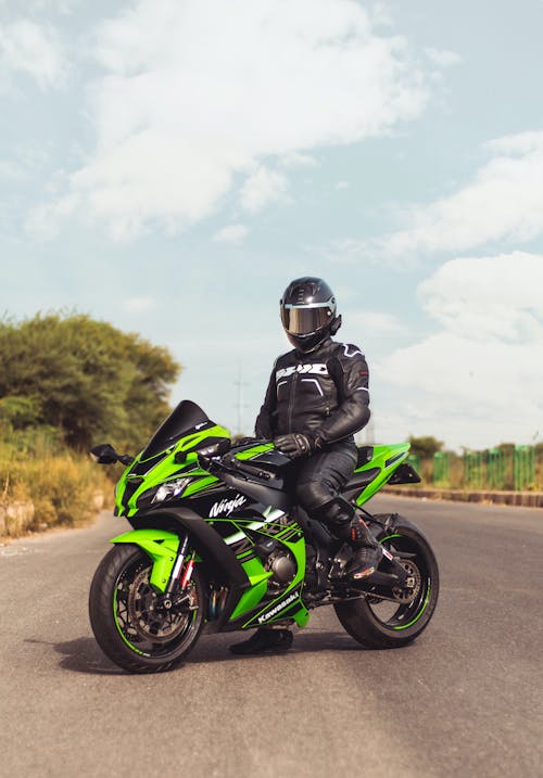 Person In Black Helmet Riding on a Green Motorbike