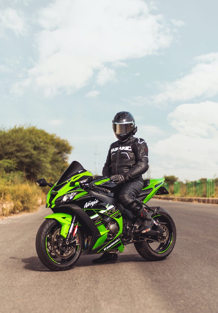 Person In Black Helmet Riding On A Green Motorbike