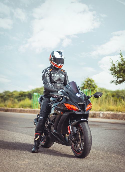 Free A motorcyclist wearing full protective gear sits on a sleek sports bike on an open road. Stock Photo