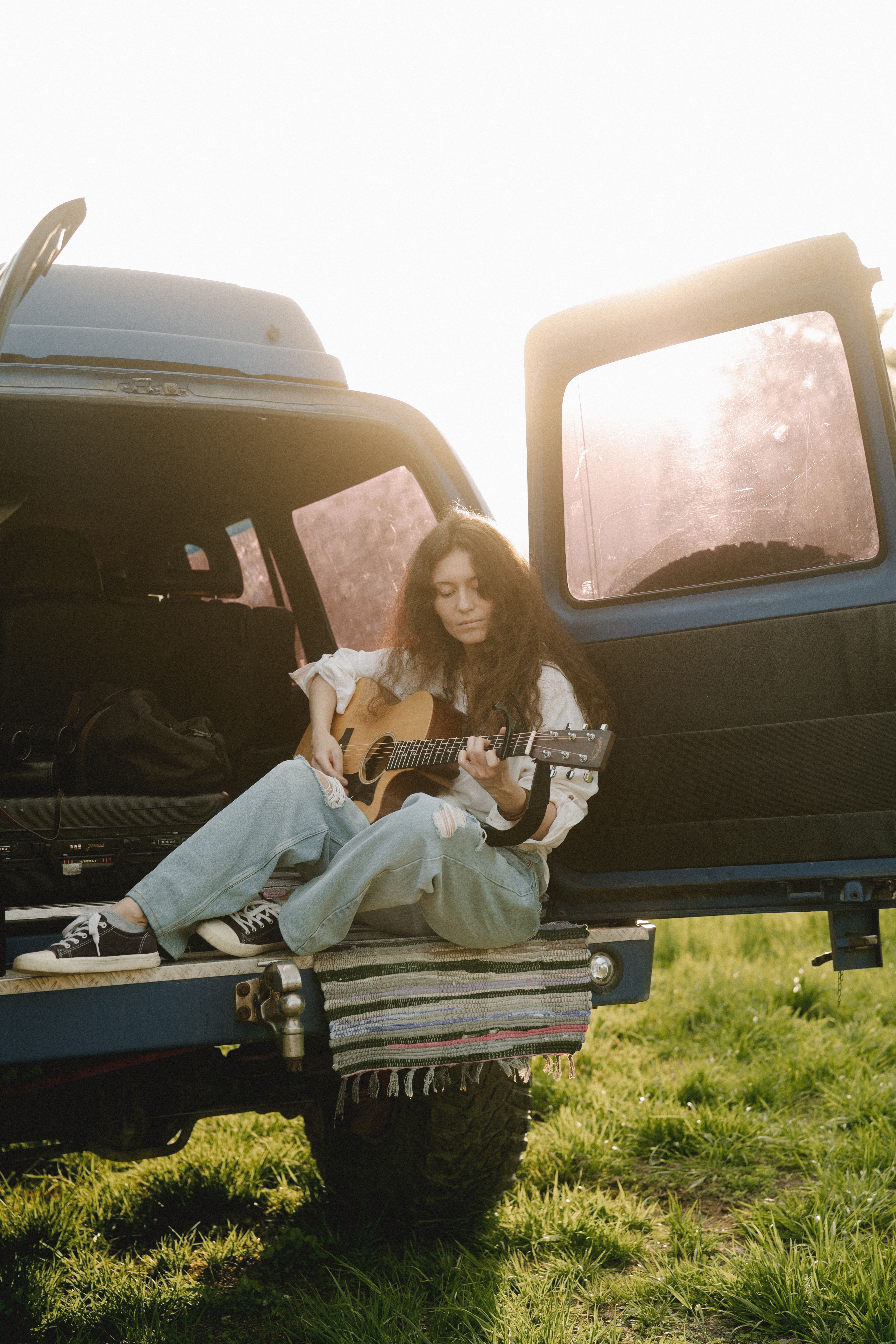 woman sitting in trunk playing a guitar