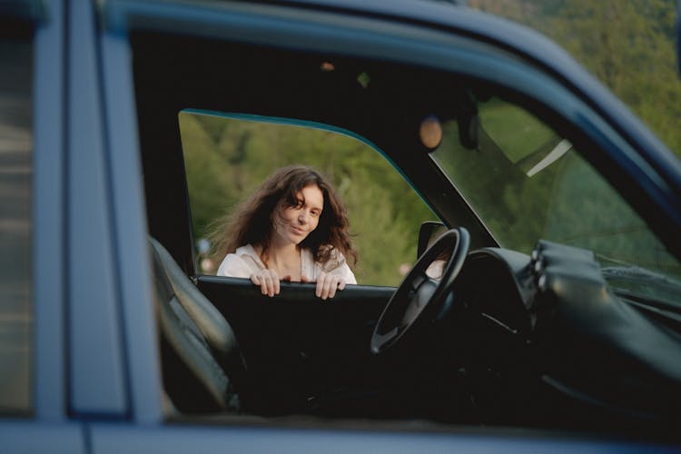 Woman Smiling While Holding On A Car Door