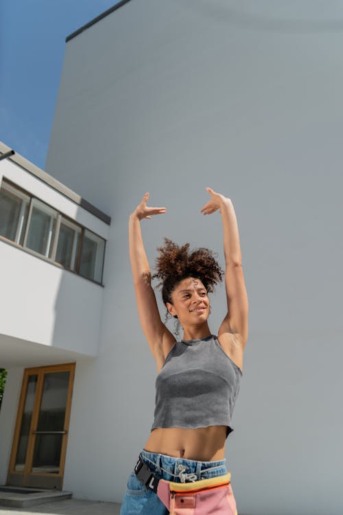 Free A Woman in Gray Tank Top Raising Her Hands Stock Photo