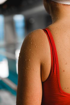 A close-up view of a swimmer wearing a red bathing suit, adorned with water droplets.