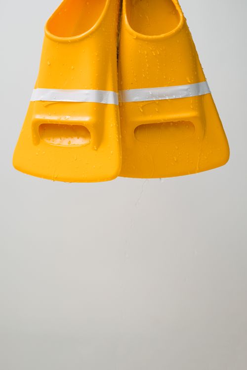 Free Bright yellow swim flippers with water droplets, perfect for aquatic activities. Stock Photo
