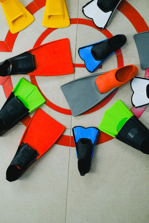 Free Various colorful swim fins arranged on a circular red target pattern, perfect for aquatic sports and activities. Stock Photo