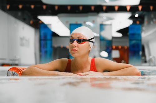 A Woman Wearing Goggles and Swimming Cap Near the Pool Side