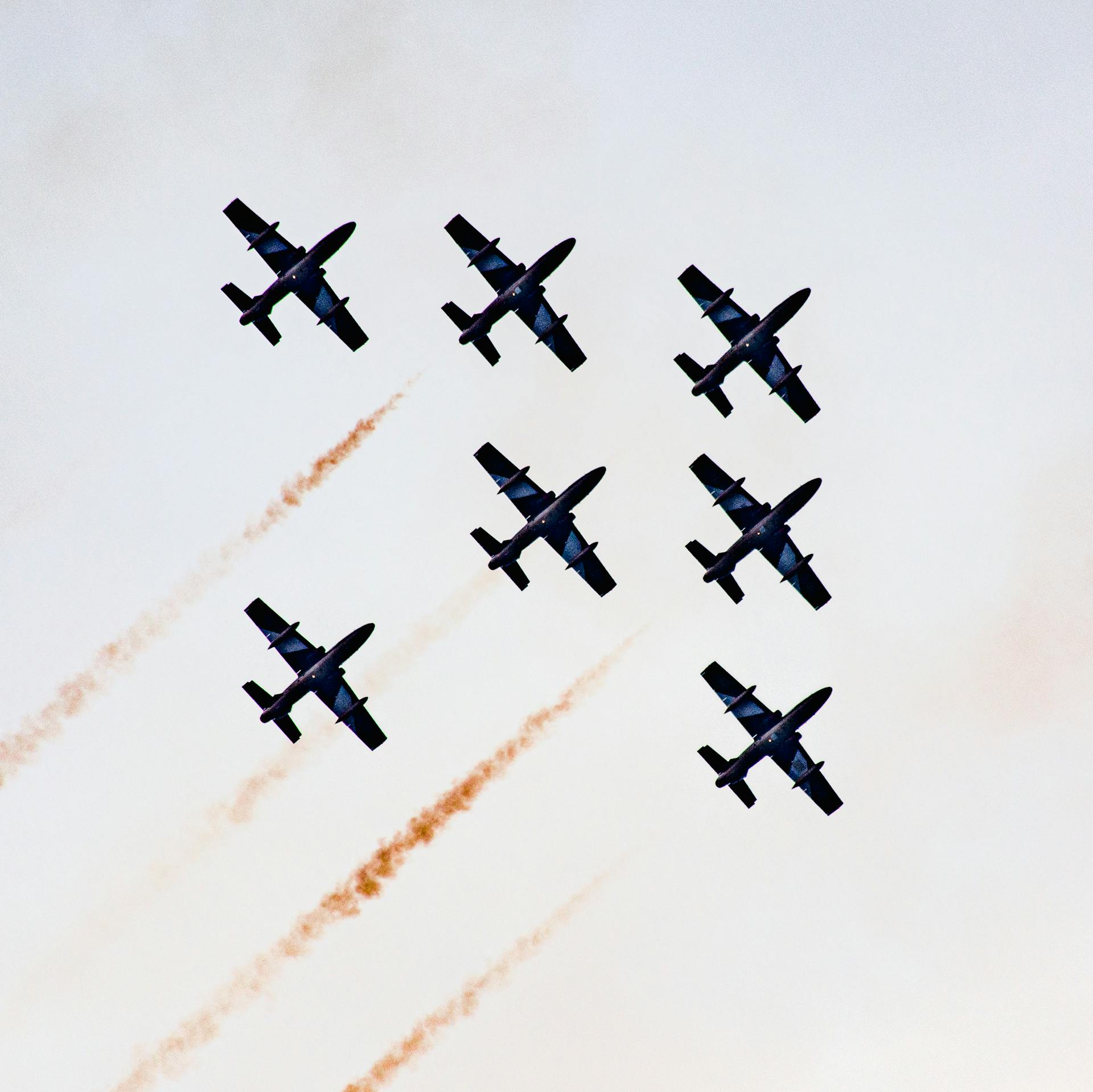 A fleet of aircrafts flying in formation, leaving contrails in a clear sky, perfect for aviation enthusiasts.