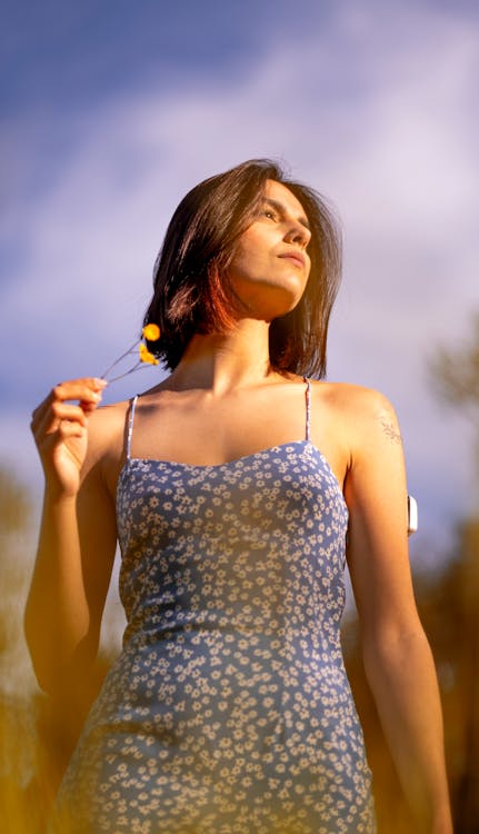 Woman in White and Black Spaghetti Strap Top Holding Yellow Flower