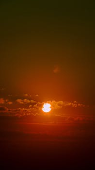 A stunning sunset showcasing vibrant orange hues surrounded by clouds, creating a dramatic skyscape.