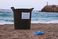 Black and White Plastic Bucket on Brown Sand Near Blue Textile