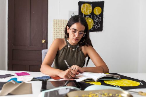 Free Young female fashion designer sketching ideas at her workspace. Stock Photo