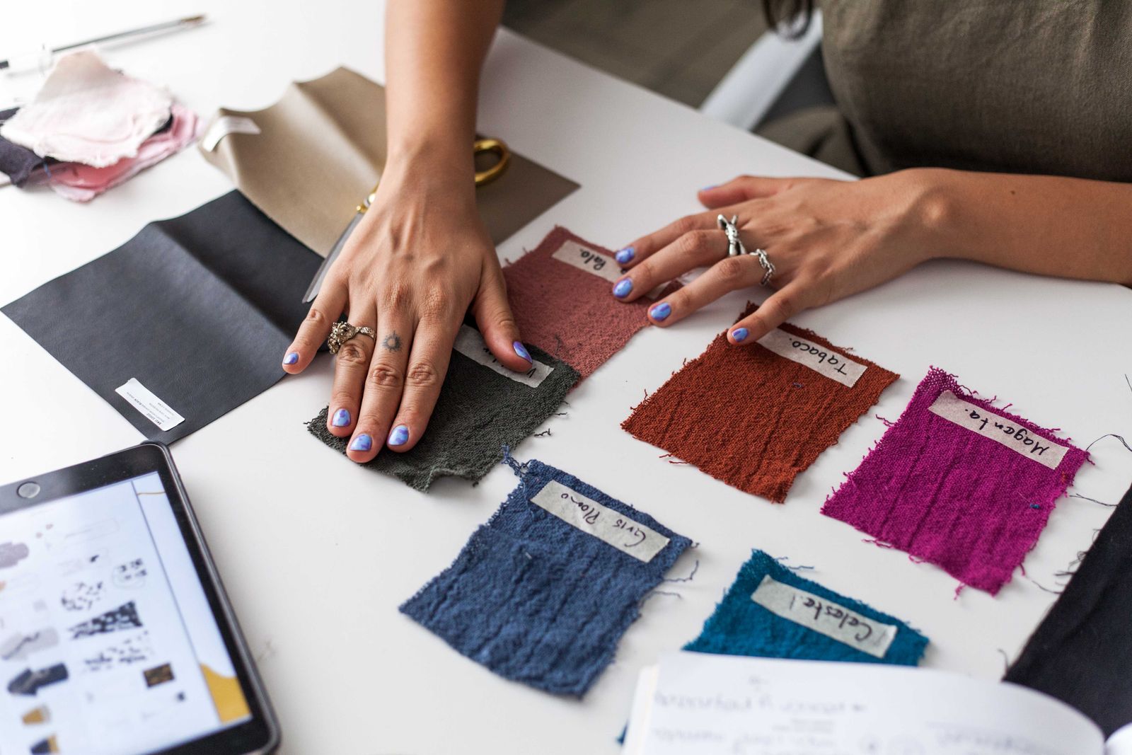 A designer laying out fabric swatches beside a tablet