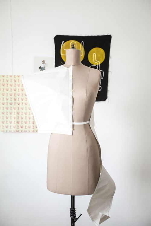 Free Female mannequin draped with white fabric in a fashion design studio, highlighting dressmaking process. Stock Photo