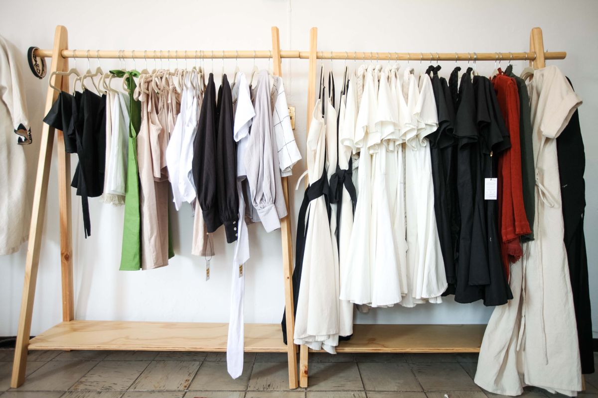 A variety of stylish clothes hanging on a wooden rack