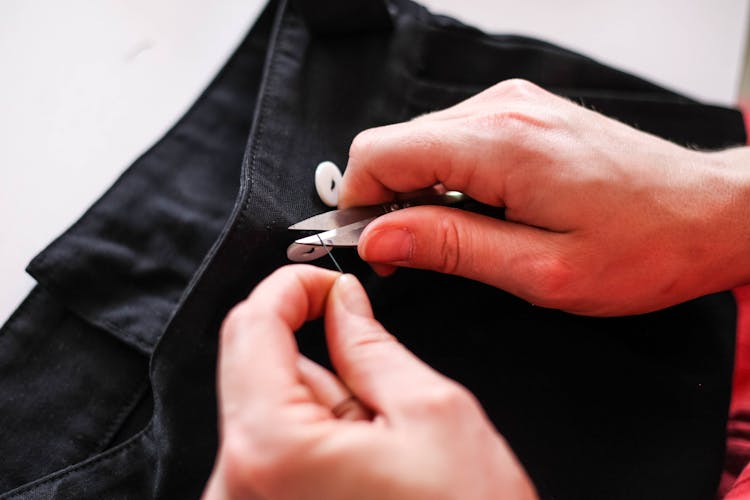 Person Cutting A Thread With Scissors