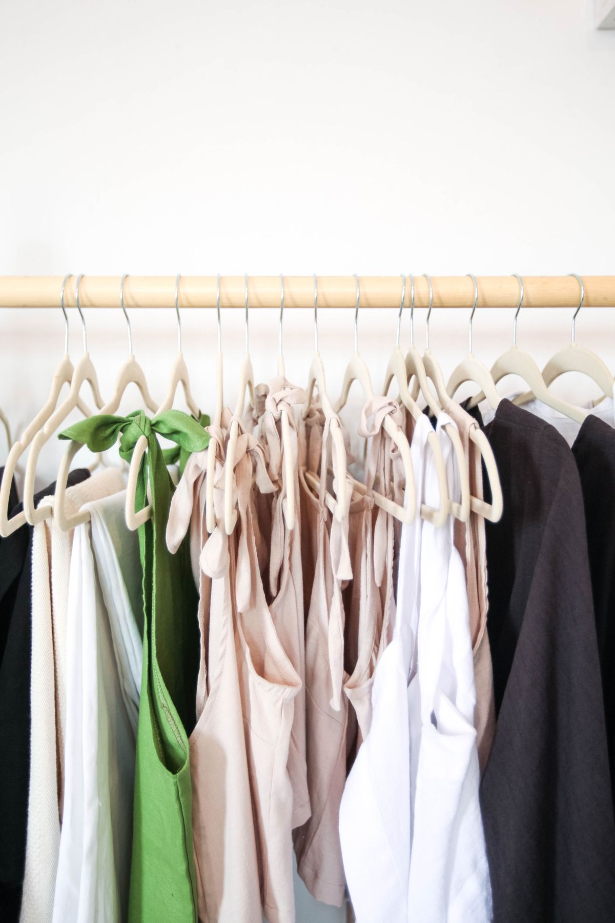 Arara minimalista com peças femininas em tons neutros formando guarda-roupa cápsula